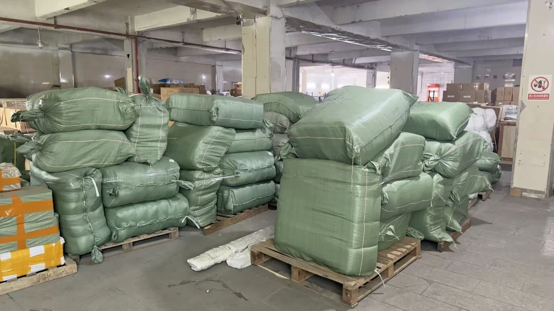 Stacked green woven cargo sacks on warehouse pallets, insured for transit to Malaysia