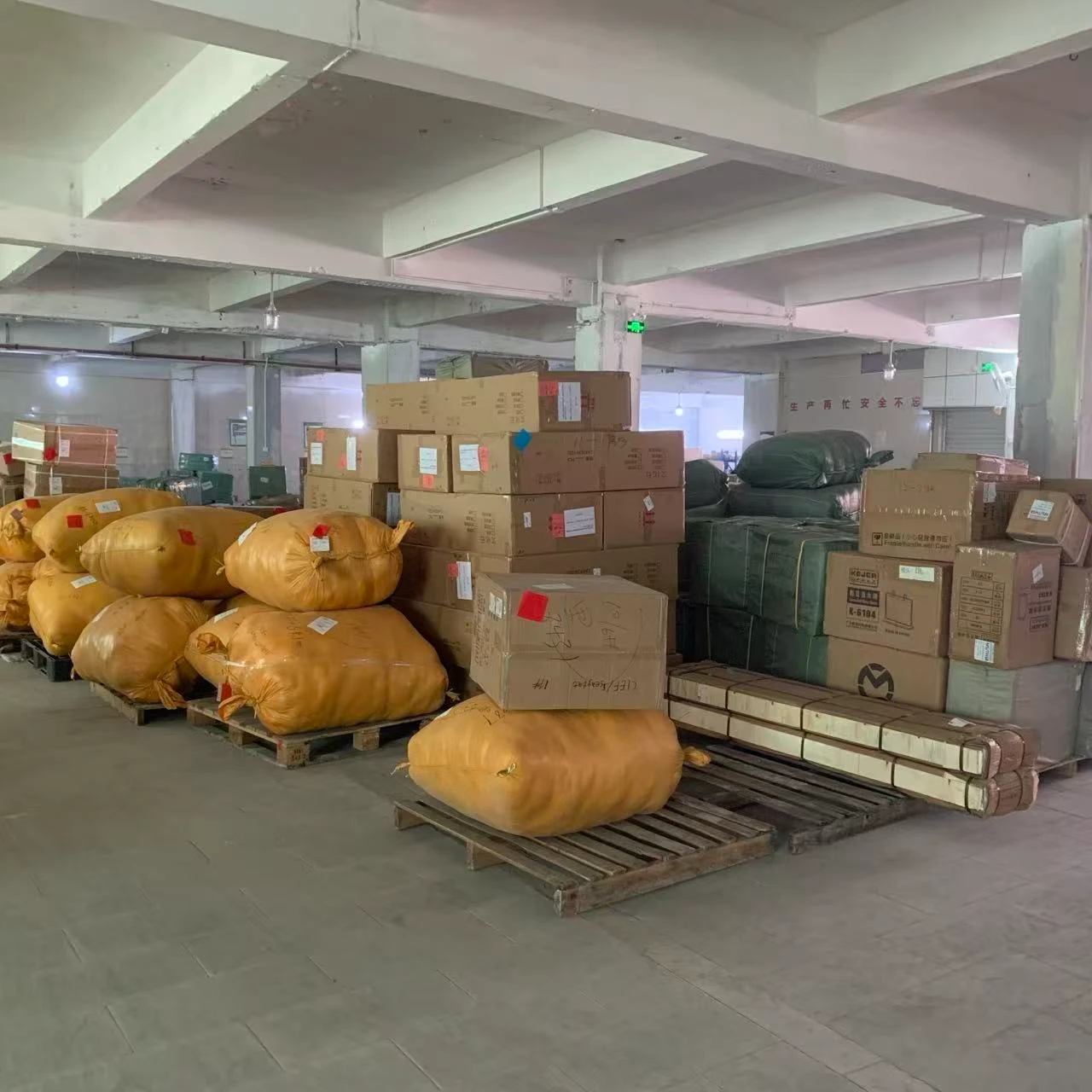 Warehouse pallets of cartons, woven cargo sacks, and bundled goods ready for consolidation and shipment to Malaysia